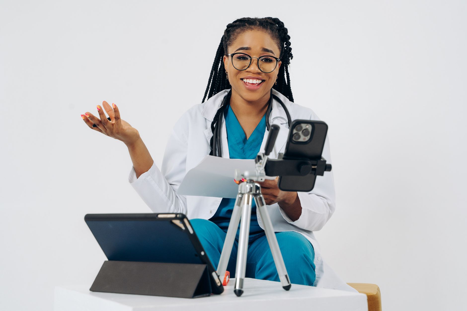 Una persona joven pensativa, revisando notas en un cuaderno después de una consulta médica virtual en Costa Rica, con una computadora y un teléfono cerca.