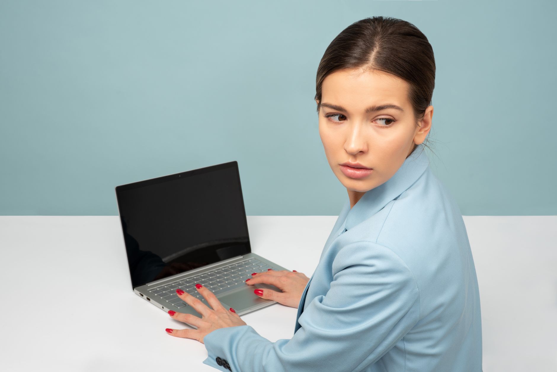 Una persona joven pensativa, revisando notas en un cuaderno después de una consulta médica virtual en Costa Rica, con una computadora y un teléfono cerca.