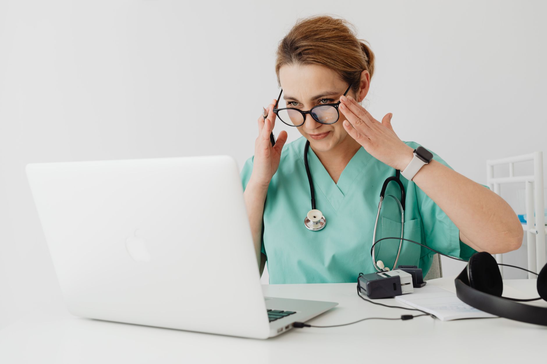 Una persona joven revisando una lista de medicamentos en su teléfono o tableta, con un fondo borroso de un hogar acogedor, preparándose para una consulta médica virtual.