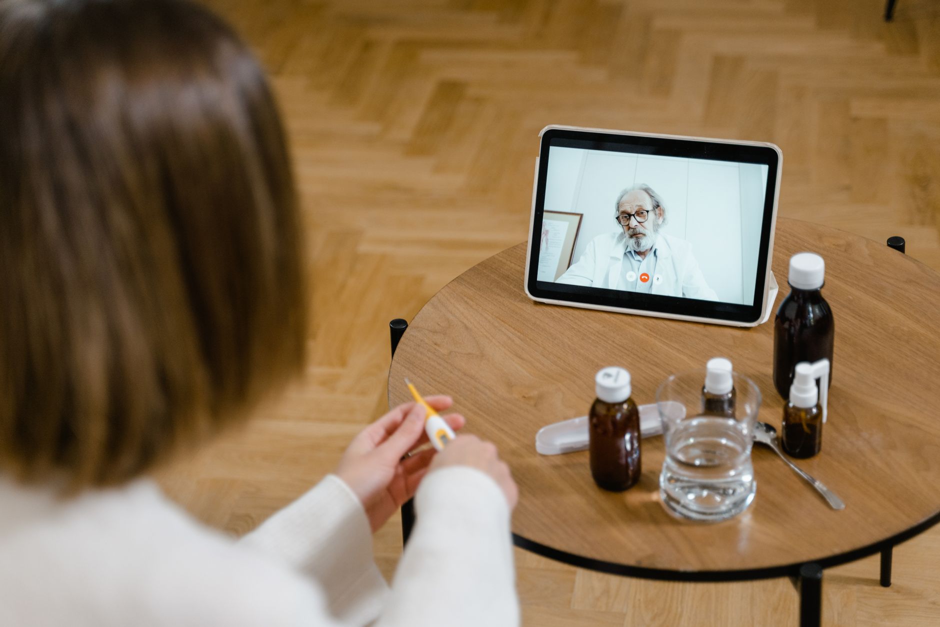 Una persona joven conversando con un médico virtual sobre una receta médica en una pantalla, con un cuaderno y lápiz a mano.