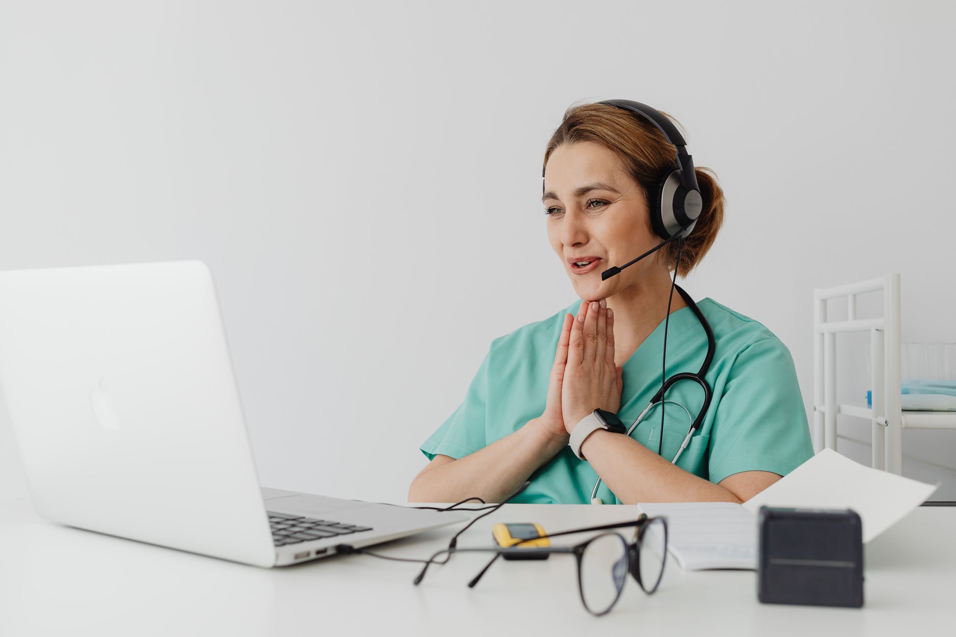Una persona joven y atenta haciendo una videollamada con un médico, con una libreta y lápiz a su lado, simbolizando una consulta médica online bien preparada.