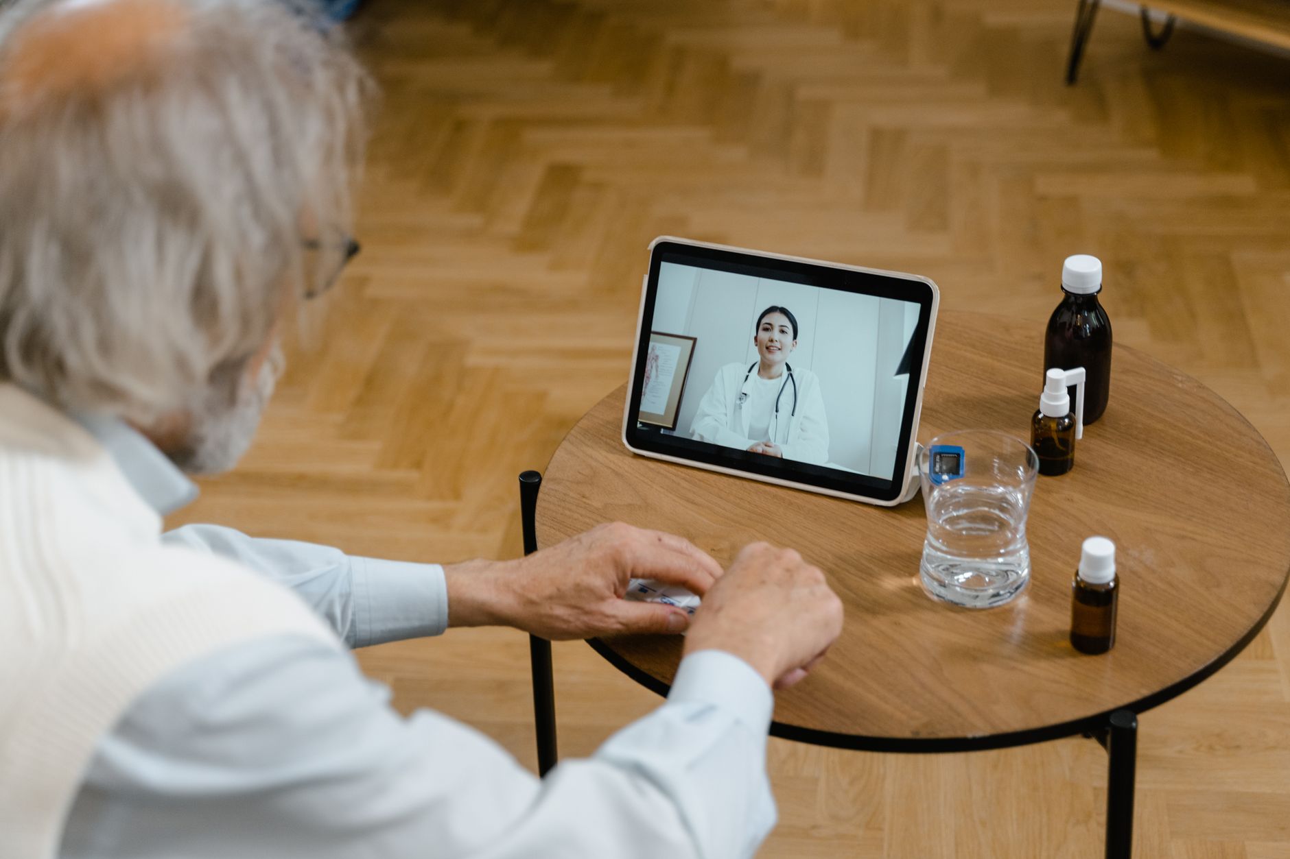 Una persona joven y atenta interactuando con una pantalla de computadora durante una consulta médica virtual, con un cuaderno y un lápiz a su lado.