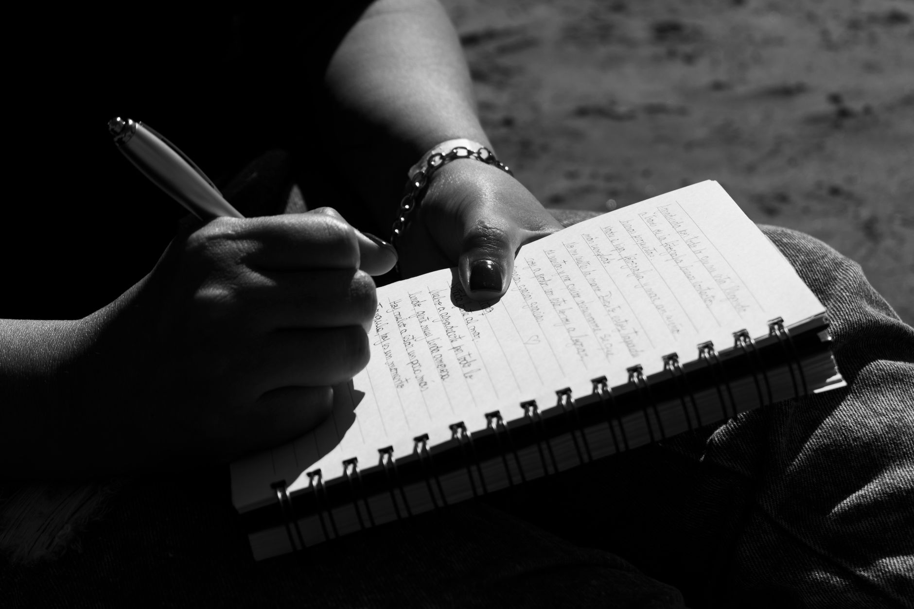 Una persona joven en Costa Rica tomando notas en un cuaderno sobre sus síntomas, con un teléfono o tablet cerca, preparándose para una consulta médica virtual.