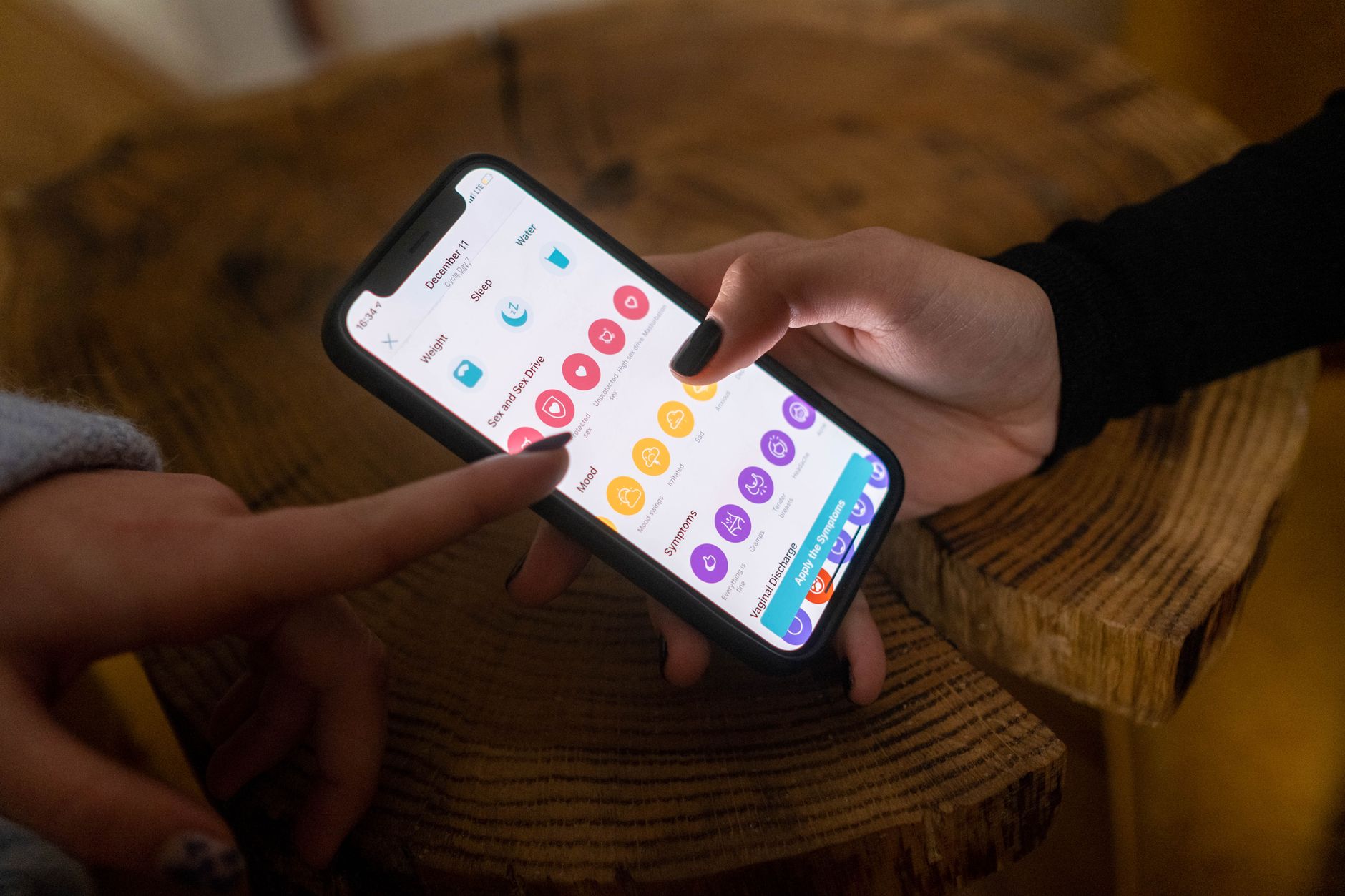 Una persona joven en Costa Rica tomando notas en un cuaderno sobre sus síntomas, con un teléfono o tablet cerca, preparándose para una consulta médica virtual.